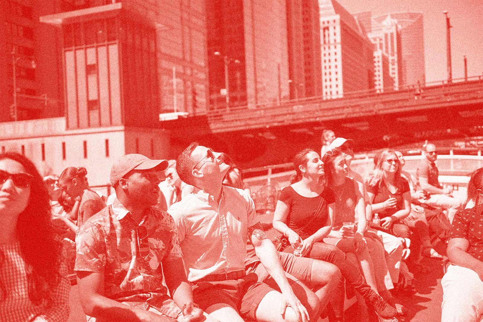 Image of a group looking up at skyscrapers on a river boat tour. The image has a red overlay.