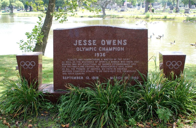 Headstone for Jesse Owens, Olympic Champion. Red/brown marble with olympic rings on either side.