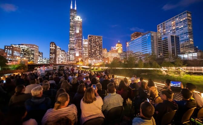 A group on a boat in the foreground with the evening skyline in the background
